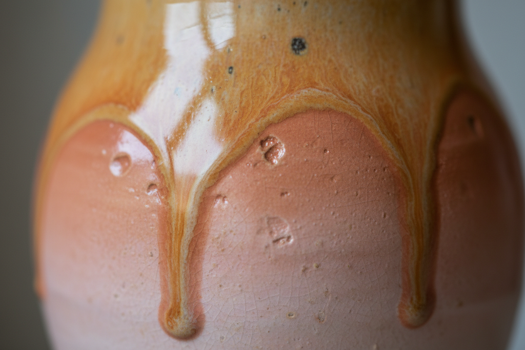 Close-up detail of layered gradient glaze on the jug body showing where amber, terracotta, and blush tones pool and blend